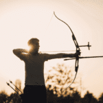 Improve target shooting techniques: A bow and arrow aimed at a bullseye on a target, with arrows scattered around the outer edges