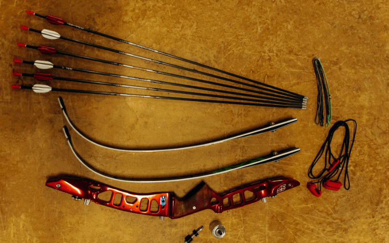 A bow and arrow being constructed with various materials in a workshop setting