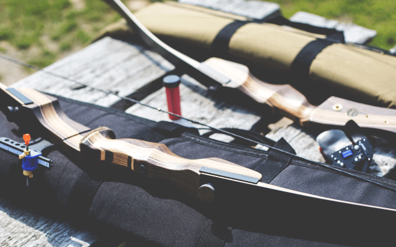 A bow and arrow set up for practice, with safety equipment and targets in a controlled outdoor setting